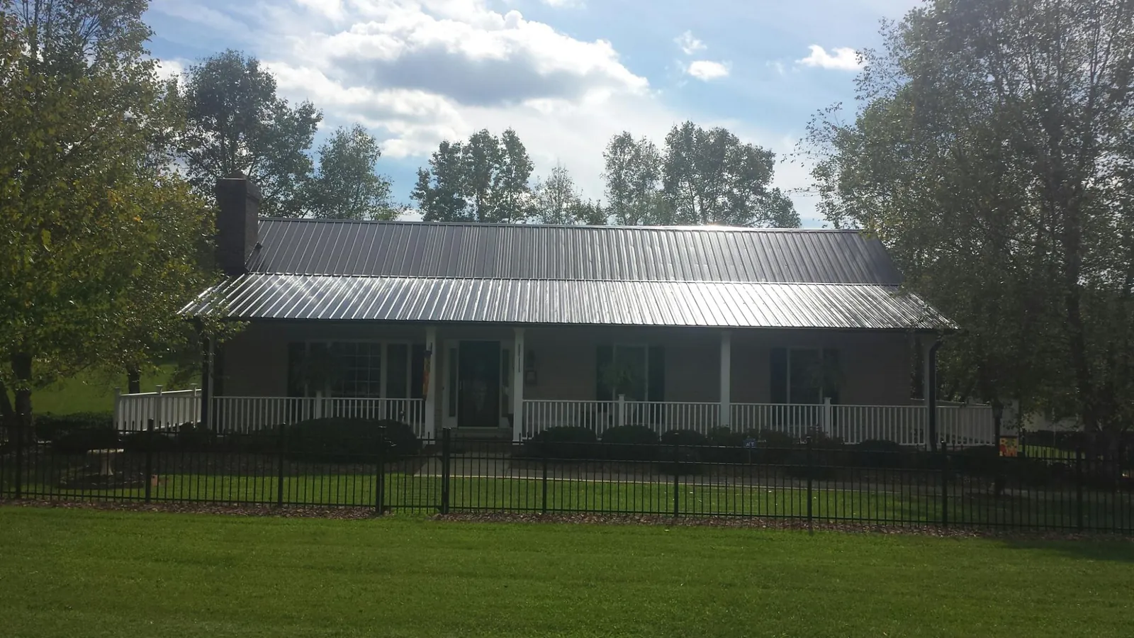Gray metal roof on a brick ranch with a full width front porch — Gutter Guard Installation work by our crew in Thayer