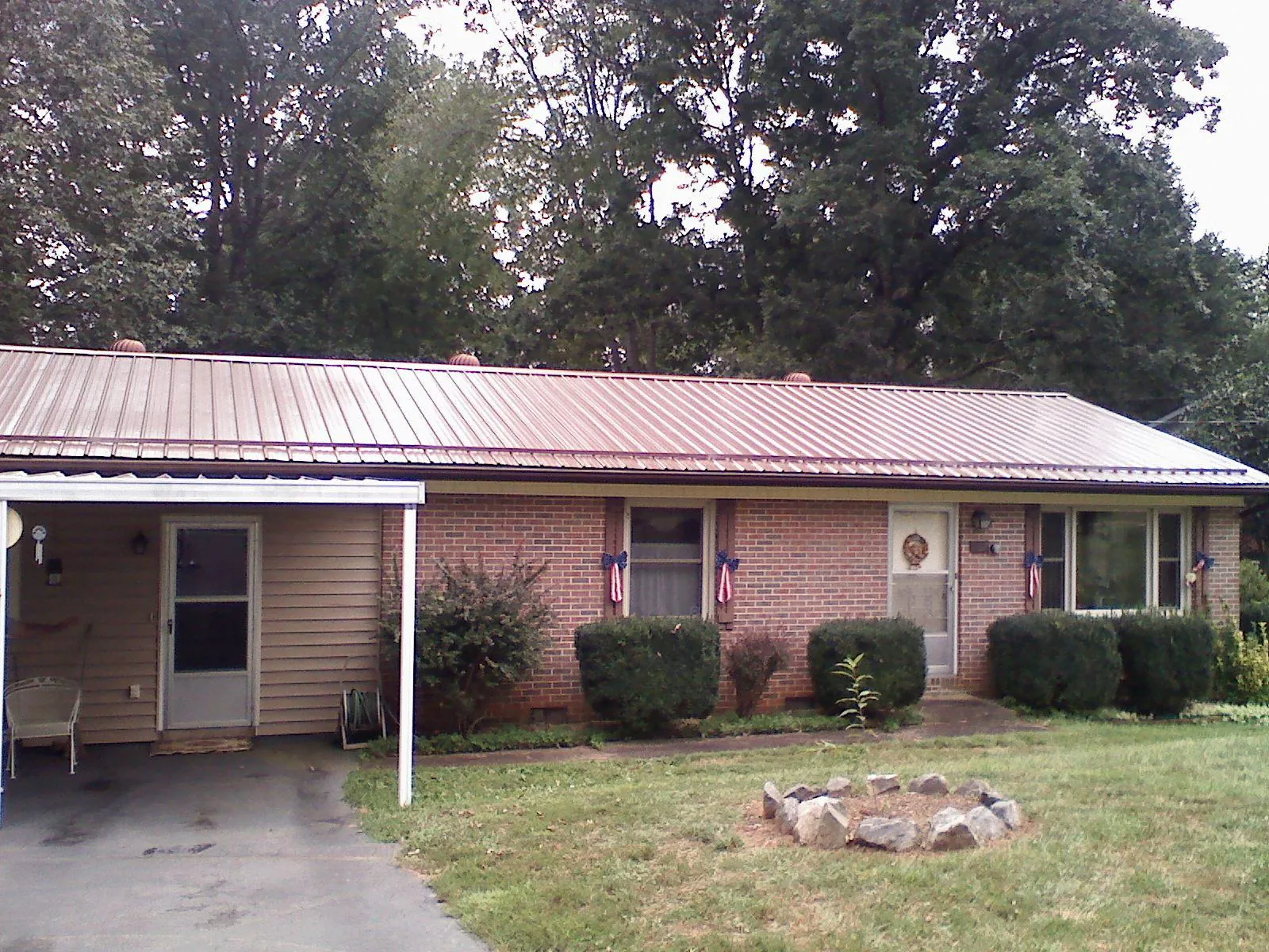 Bronze metal roof and carport on a brick ranch home — Roof Repair work by our crew in Thayer